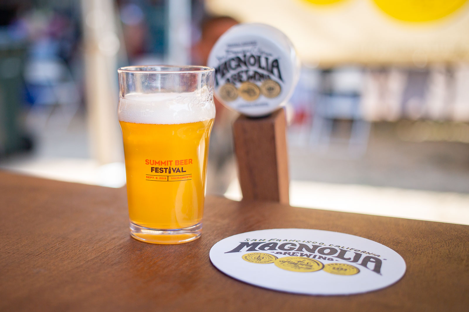 Tasting glass next to a Magnolia Brewing tap handle with Magnolia Brewing coaster.