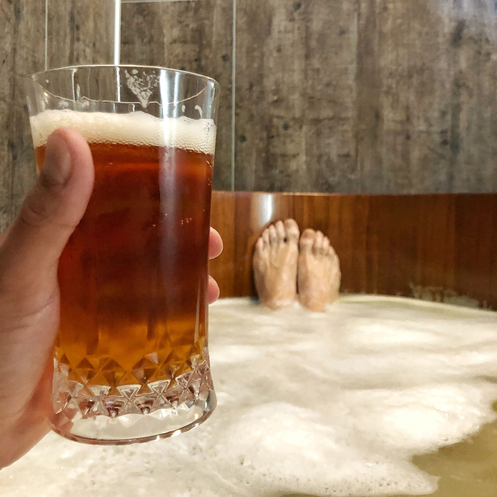 Pictured: Tim in a beer bath with his feet show and him holding a beer.