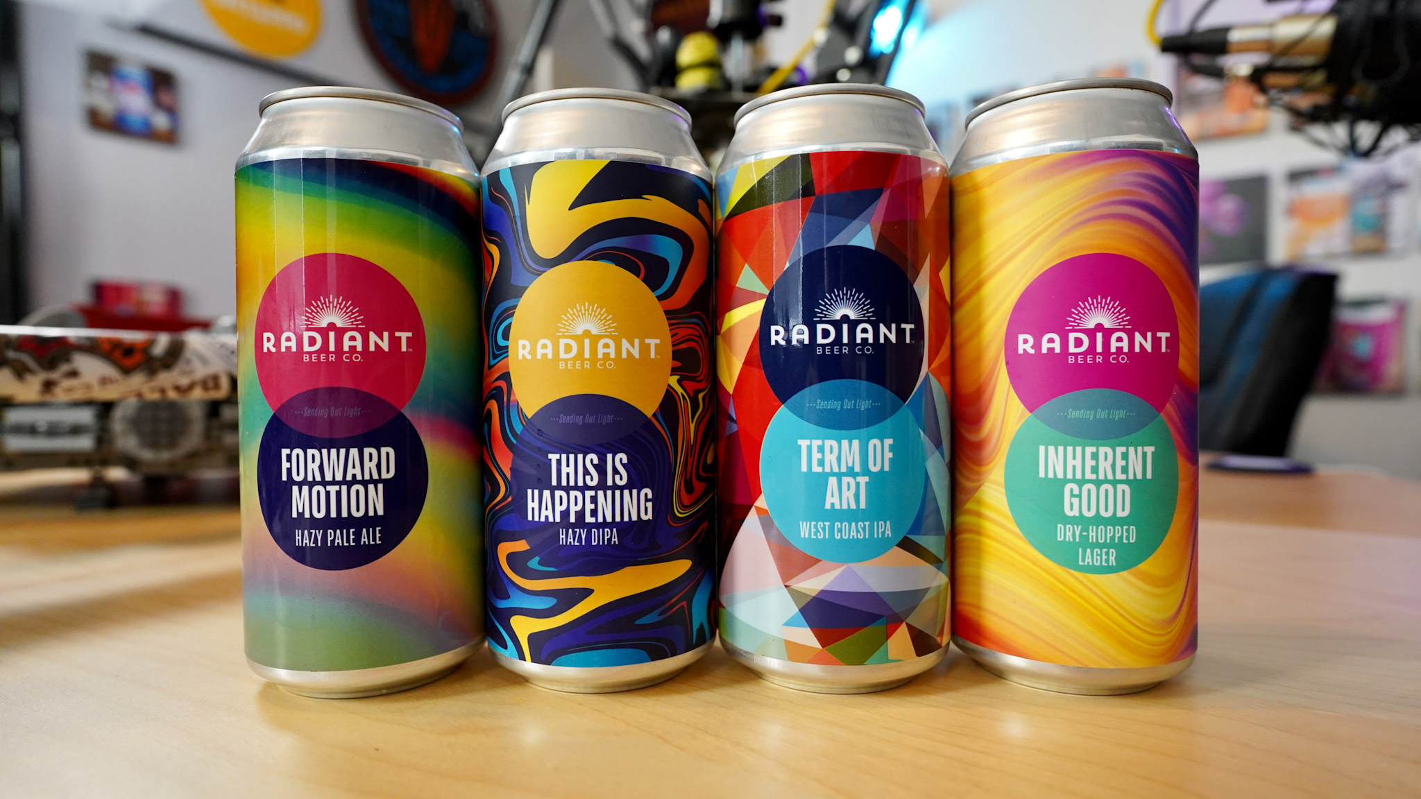Four cans of colorfully labeled beers from Radiant Beer Co.